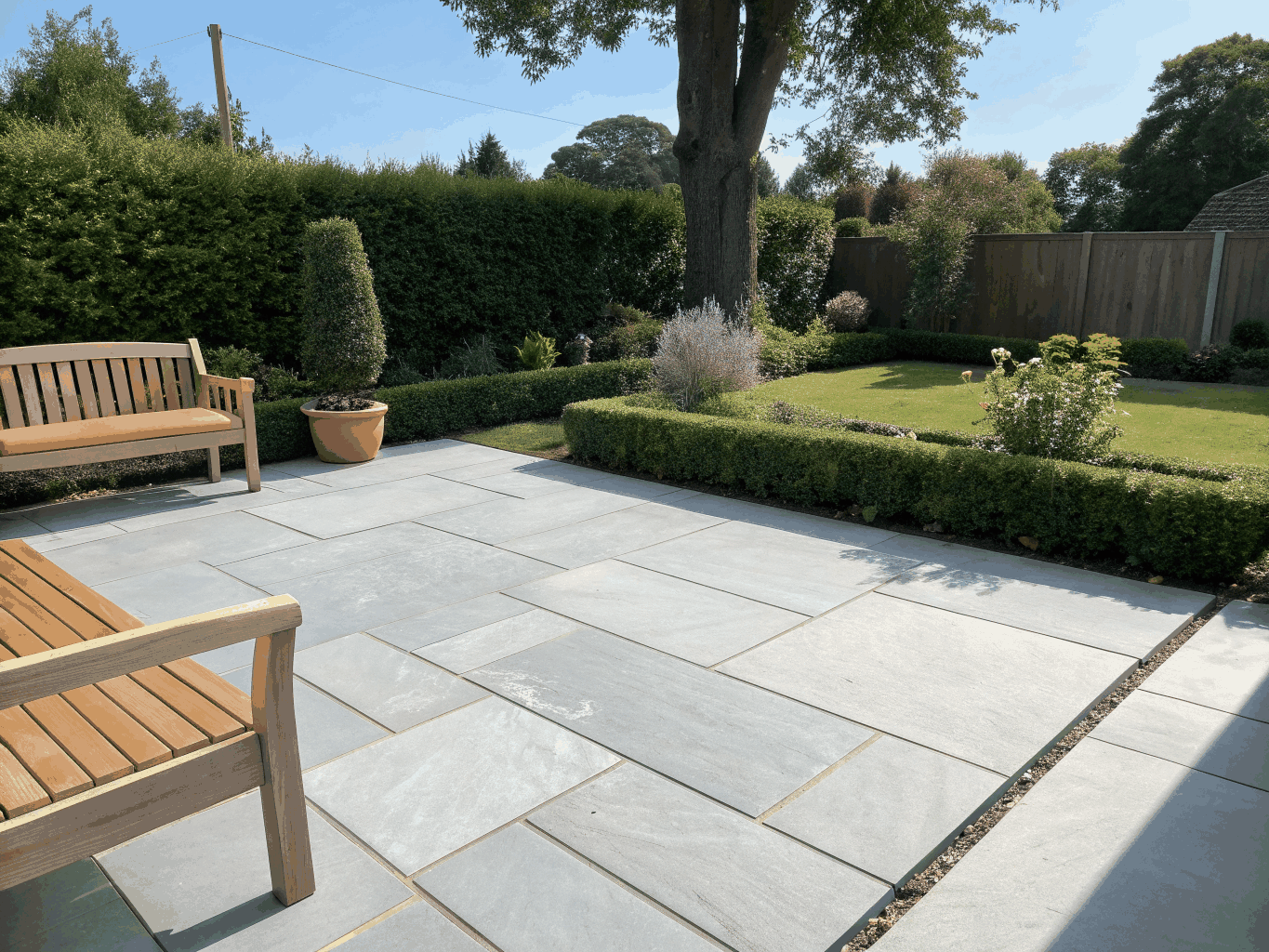 Newly laid porcelain patio with architectural border planting and manicured lawn